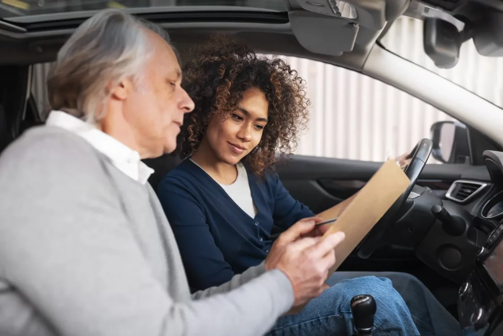 Instructor explaining how to book a driving test to learner inside a car before practical test