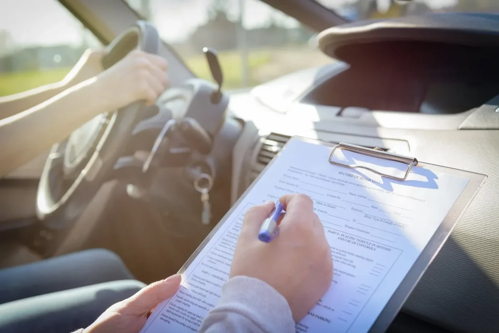Examiner marking a checklist during a learner’s road exam, showing what happens and helping explain how long is a driving test."