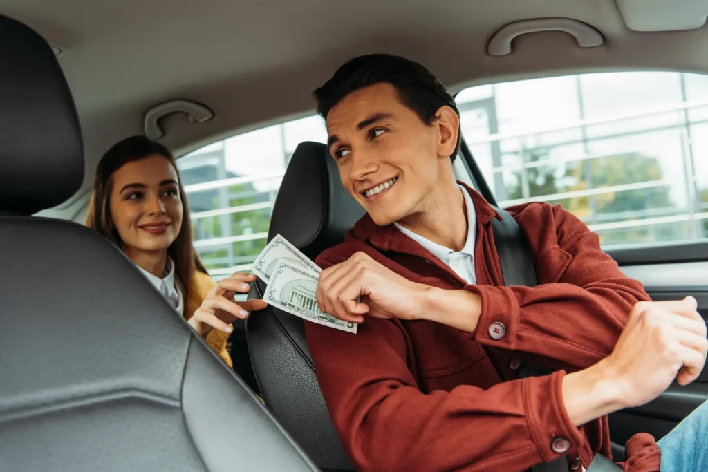 Instructor receiving payment from a learner inside a car, showing the real-life cost of driving lessons.